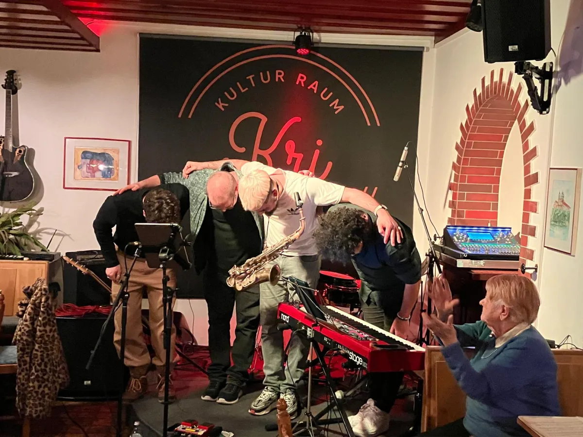 Die Musiker von Melomania verbeugen sich nach dem Konzert, eine Besucherin in der ersten Reihe applaudiert