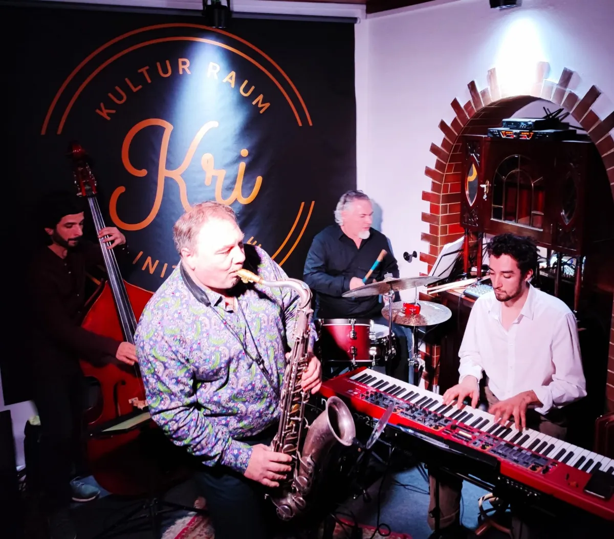 Quartett im KRI mit Saxofon, Kontrabass, Schlagzeug und Keyboard vor dem Kri-Banner