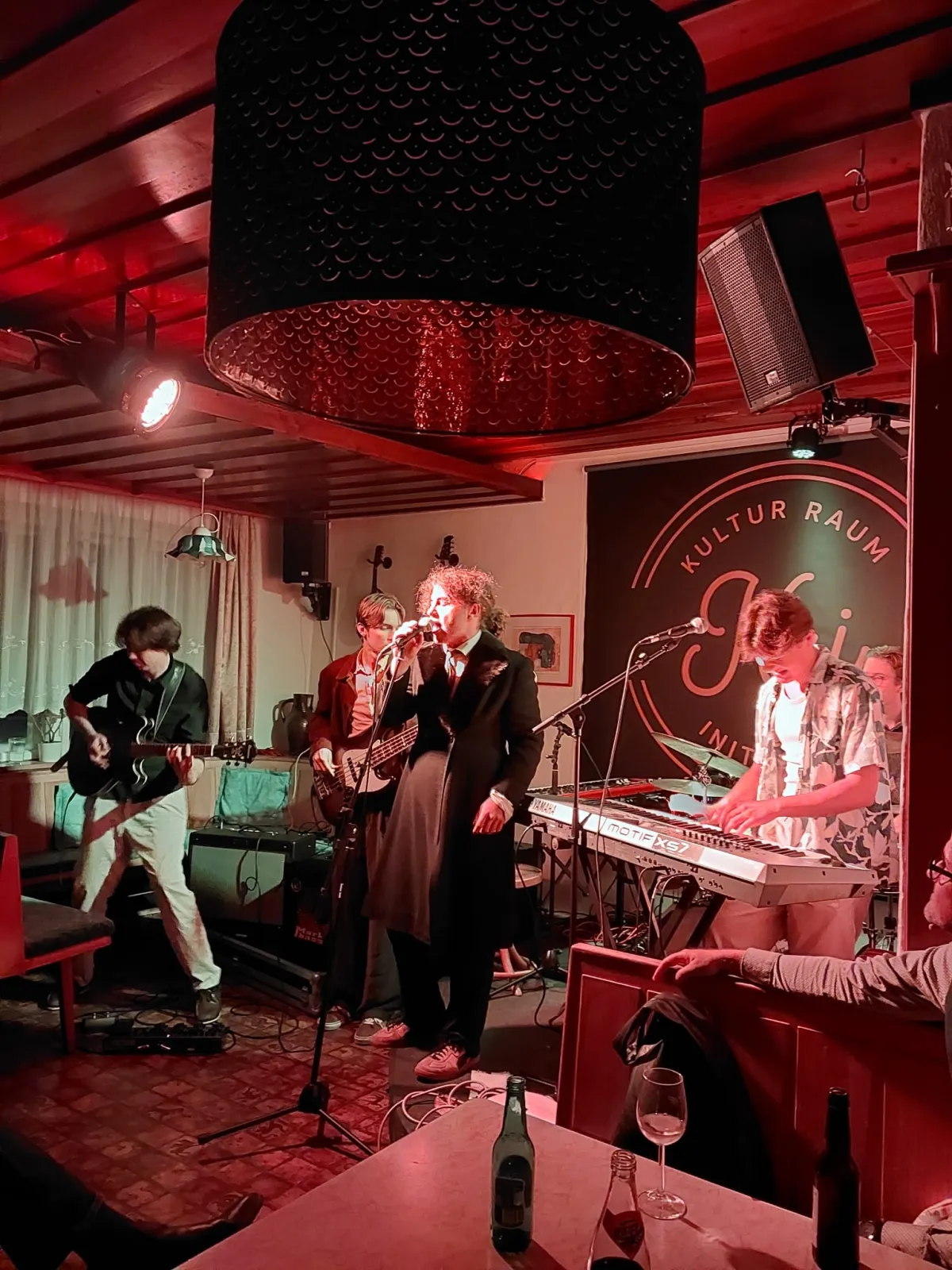 Smelly Jelly live im KRI bei rotem Licht, der Sänger im langen Mantel am Mikrofon